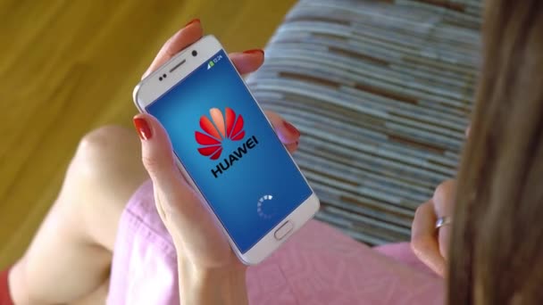 Młoda kobieta trzymając telefon komórkowy z ładowaniem Huawei mobile App konceptualnej redakcji 4k klip — Wideo stockowe