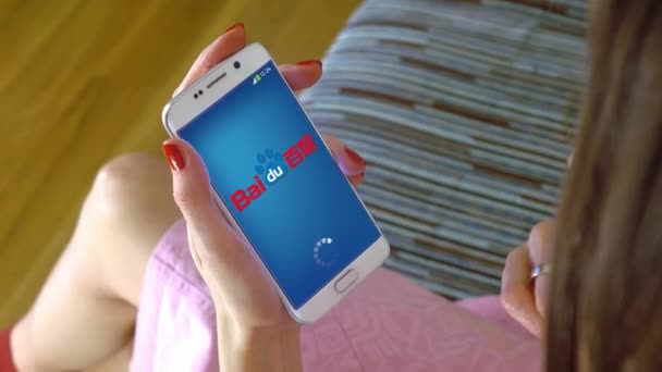 Giovane donna in possesso di un telefono cellulare con caricamento app mobile Baidu. Clip editoriale concettuale 4K — Video Stock