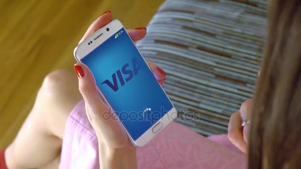 Jovem segurando um telefone celular com o aplicativo móvel Visa de carregamento. Editorial conceitual 4K clip — Vídeo de Stock