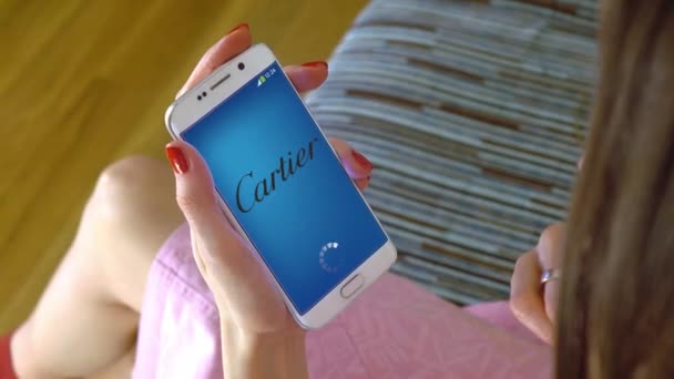 O tânără care deține un telefon mobil cu încărcarea aplicației mobile Cartier. Conceptual editorial 4K clip — Videoclip de stoc