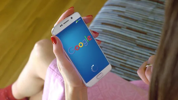 Jeune femme tenant un téléphone portable avec le chargement de l'application mobile Google. Éditorial conceptuel CGI — Photo