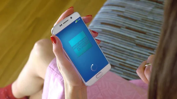 Jeune femme tenant un téléphone portable avec chargement de l'application mobile American Express. Éditorial conceptuel CGI — Photo
