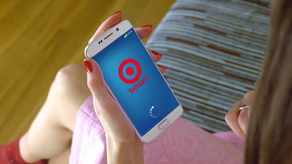 Jeune femme tenant un téléphone portable avec chargement de l'application mobile Target. Éditorial conceptuel CGI — Photo