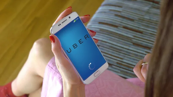 Jeune femme tenant un téléphone portable avec chargement de l'application mobile Uber. Éditorial conceptuel CGI — Photo