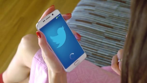 Jovem segurando um celular com o carregamento do aplicativo móvel do Twitter. Editorial conceitual 4K clip — Vídeo de Stock