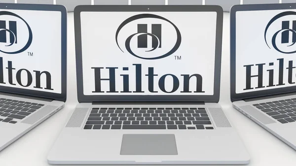 Portátiles con el logotipo de Hilton Hotels Resorts en la pantalla. Tecnología informática editorial conceptual 3D rendering — Foto de Stock