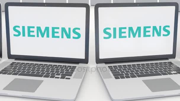 Portátiles con el logotipo de Siemens en la pantalla. Tecnología informática editorial conceptual clip 4K, bucle sin costura — Vídeos de Stock