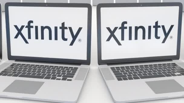 Xfinity logo üstünde belgili tanımlık perde ile dizüstü bilgisayarlar. Bilgisayar teknolojisi kavramsal editoryal 4k klip, sorunsuz döngü — Stok video