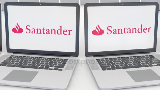 Ноутбуки с логотипом Santander Serfin на экране. Концептуальная редакционная работа по компьютерным технологиям 4К клип, бесшовный цикл — стоковое видео
