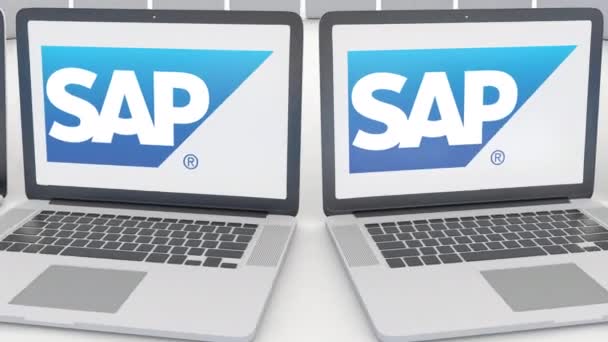 Ноутбуки с логотипом SAP SE на экране. Концептуальная редакционная работа по компьютерным технологиям 4К клип, бесшовный цикл — стоковое видео