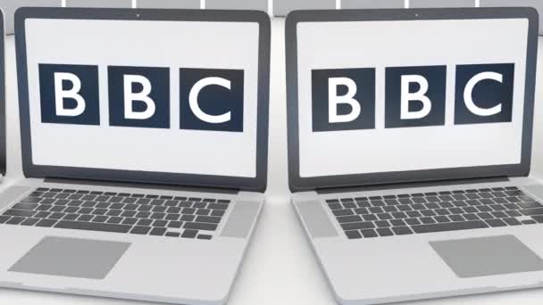 Portátiles con el logotipo de la BBC de British Broadcasting Corporation en la pantalla. Tecnología informática editorial conceptual clip 4K, bucle sin costura — Vídeos de Stock