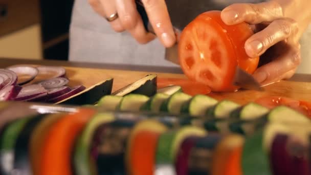 Mujer joven cortando jugoso tomate rojo. Cocinar ratatouille casero. 4K primer plano de vídeo — Vídeo de stock