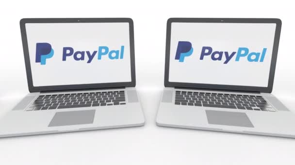 Ноутбуки с логотипом PayPal на экране. Концептуальная редакционная работа по компьютерным технологиям 4К клип, бесшовный цикл — стоковое видео