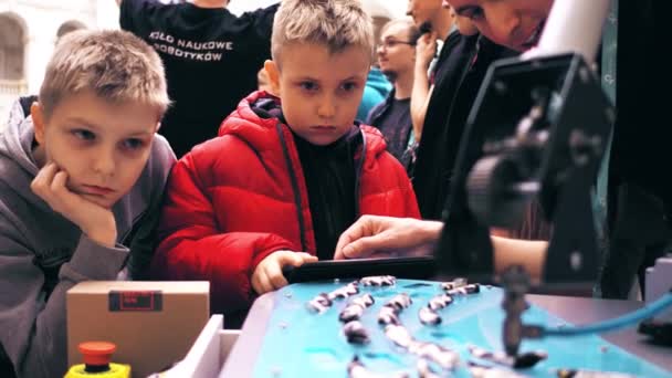 ワルシャワ, ポーランド - 2017 年 3 月 4 日。エンジニアは、少年にロボット アーム操作を示します。4 k ビデオ — ストック動画