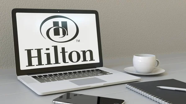 Portátil con el logotipo de Hilton Hotels Resorts en la pantalla. Moderno lugar de trabajo editorial conceptual 3D rendering — Foto de Stock