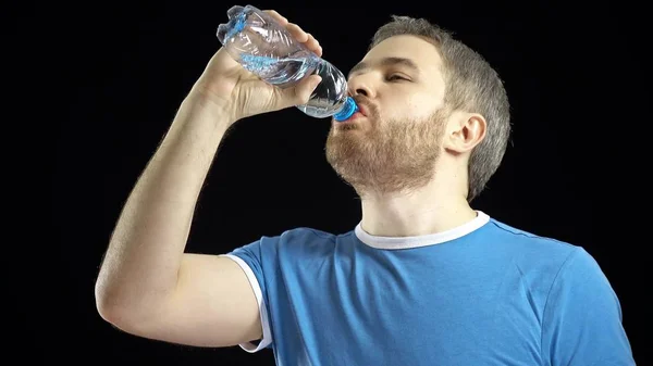 Hombre guapo de pelo gris en camiseta azul bebiendo agua de la botella de pastic. Fondo negro — Foto de Stock
