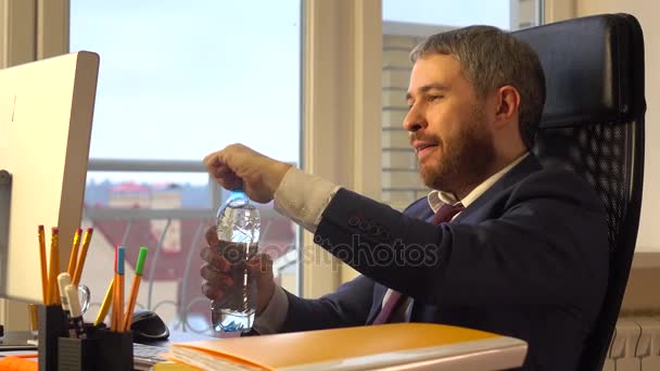 自信的年轻商人喝水在他的办公桌。4 k 视频 — 图库视频影像