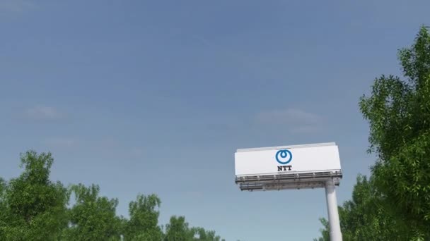 Conduciendo hacia la cartelera publicitaria con el logotipo NTT de Nippon Telegraph y Telephone Corporation. Editorial 3D renderizado 4K clip — Vídeo de stock