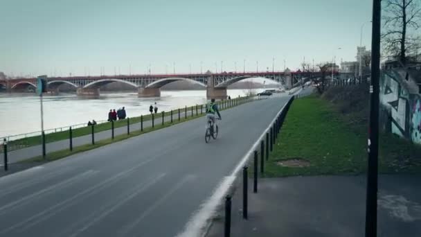 空中的年轻人骑他的自行车，沿着晚上河堤的跟踪拍摄。4 k 视频 — 图库视频影像