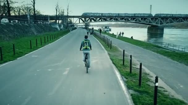 GARANTIA, POLÓNIA - MARÇO, 27, 2017. Rastreamento aéreo tiro de motociclista masculino solitário andando de bicicleta ao longo do dique do rio à noite. Clipe 4K — Vídeo de Stock