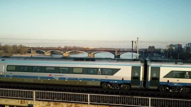 WARSAW, POLAND - MARCH, 27, 2017. Aerial tracking shot of modern passenger train moving on railway bridge across the river. 4K clip — Stock Video