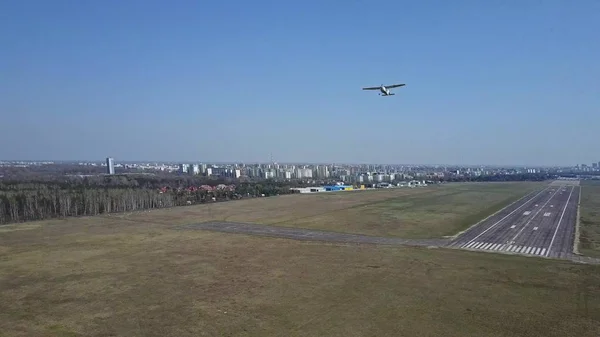 ภาพถ่ายทางอากาศของเครื่องบินใบพัดขนาดเล็กที่ขึ้นจากรันเวย์สนามบินในวันที่แดด — ภาพถ่ายสต็อก
