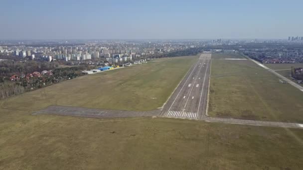 晴れた日に市空港の滑走路近くを飛んでいる小さなプロペラ飛行機の空中ショットは。4 k ビデオ — ストック動画