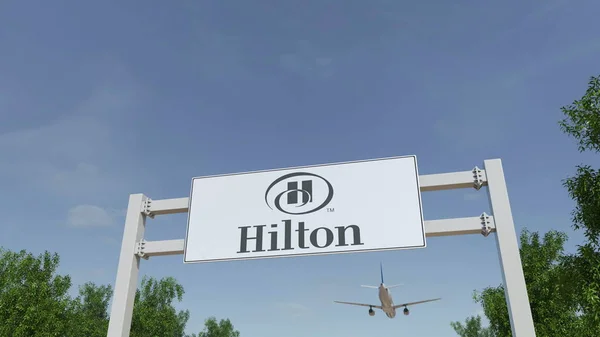 Літак, що летить над реклама Рекламний щит з логотипом Hilton готелів курортів. Редакційні 3d-рендерінг — стокове фото