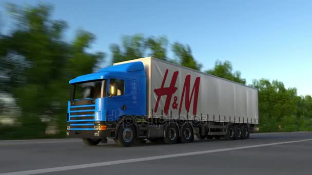 Camión semi de carga con el logotipo de H M conduciendo a lo largo de la carretera forestal, bucle sin costuras. Clip editorial 4K — Vídeo de stock