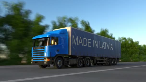 Fortkörning frakt semi truck med gjort i Lettland bildtext på släpet. Road cargo transport. Sömlös loop 4k klipp — Stockvideo