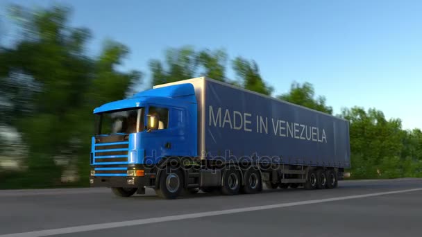 Velocidade semi-caminhão de carga com MADE IN VENEZUELA legenda no reboque. Transporte rodoviário de carga. Loop sem costura 4K clip — Vídeo de Stock