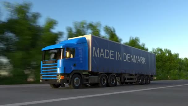 Speeding freight semi truck with MADE IN DENMARK caption on the trailer. Road cargo transportation. Seamless loop 4K clip — Stock Video
