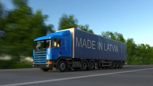 Грузовой полугрузовик с надписью MADE IN LATVIA на прицепе. Автомобильные перевозки грузов. 3D рендеринг — стоковое фото