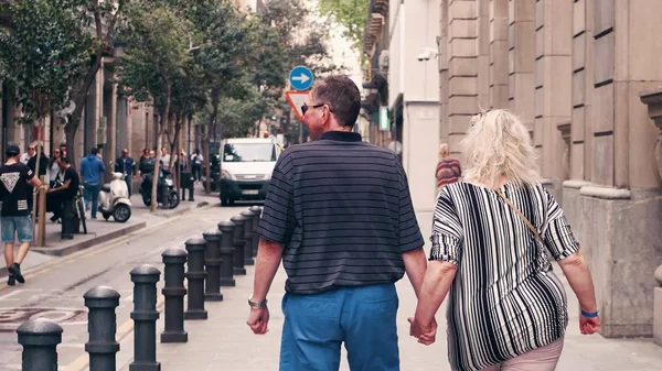 BARCELONA, SPAIN - APRIL, 15, 2017. Mature couple walking holding hands along the street — Stock Photo, Image