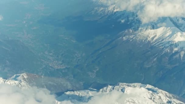 Picos nevados y pueblos alpinos distantes en un valle. Tiro aéreo 4K — Vídeo de stock