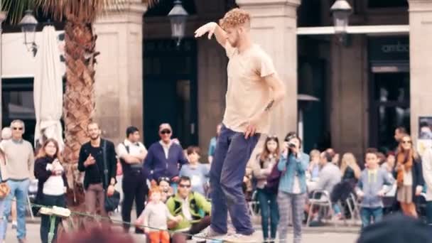БАРСЕЛОНА, ИСПАНИЯ - АПРЕЛЬ, 16 апреля 2017 года. Тонкий троп акробат выступает на улице. Балансируя на раскачивающемся ремне. 4K клип — стоковое видео