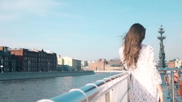 МОСКВА, РОССИЯ - 29 апреля 2017 г. Молодая женщина в белом платье стоит на палубе речного экскурсионного судна. Памятник Петру I. 4К выстрел — стоковое видео