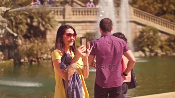 BARCELONA, SPAIN - APRIL, 16, 2017. Young woman making selfies with a cellphone near the park fountain. 4K video — Stock Video