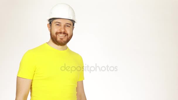 Portré, jóképű, vidám Konstrukciós mérnök vagy építész sárga póló és kemény kalap, fehér háttérrel. 4k videóinak — Stock videók