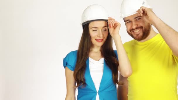 Retrato de dois engenheiros alegres ou arquitetos vestindo tinha chapéus contra fundo branco. Clipe 4K — Vídeo de Stock