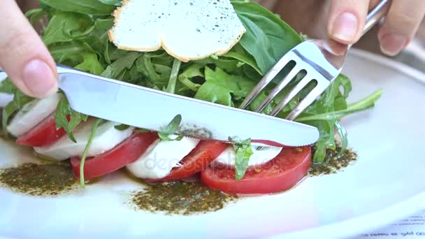Vrouw plukken stuk van tomaat en mozzarella kaas. Caprese salade. 4k video — Stockvideo