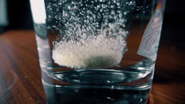 Comprimido efervescente caindo em vidro de água. 4K close-up tiro em câmera lenta — Vídeo de Stock