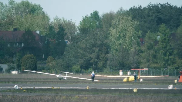 Lente de teleobjetivo disparada de dos hombres remolcando un planeador en el suelo más allá de la bruma de calor de la pista. Concepto de aviación amateur asequible — Foto de Stock