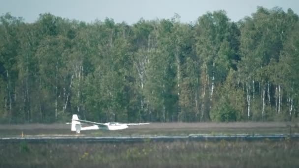 Telephoto lens shot of a glider landing beyond runway heat haze. 4K video — Stock Video