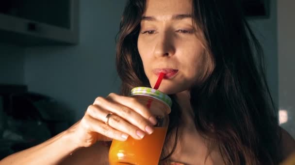 Hermosa joven bebiendo jugo de naranja fresco en casa. Vídeo 4K — Vídeos de Stock