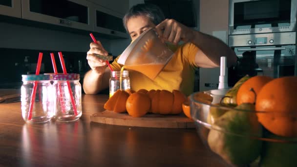 Un bell'uomo barbuto che fa e beve succo d'arancia fresco a casa. Video 4K — Video Stock