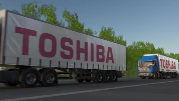 Camions semi-remorques de fret avec logo Toshiba Corporation conduisant le long de la route forestière, boucle transparente. Clip éditorial 4K — Video