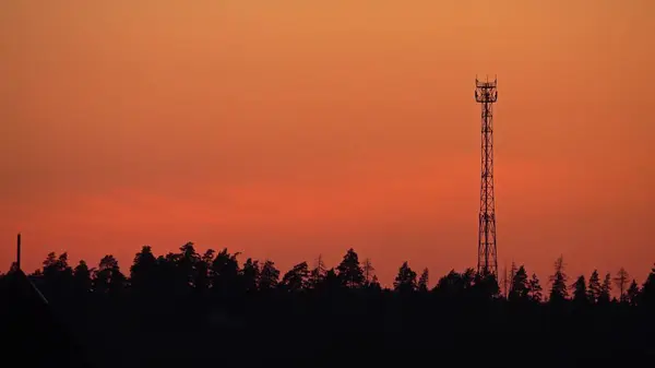 Silhueta de uma torre de célula contra céu de pôr-do-sol cor-de-laranja — Fotografia de Stock