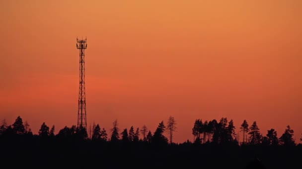 Siluet dari menara sel terhadap oranye matahari terbenam langit. Video 4K — Stok Video