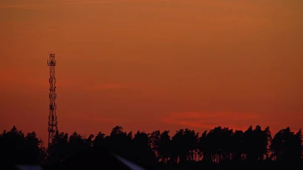 Силуэт сотовой вышки или сотового участка против оранжевого вечернего неба — стоковое фото